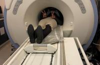 A work experience student, disappearing into a mock MRI scanner, but seeming happy about it