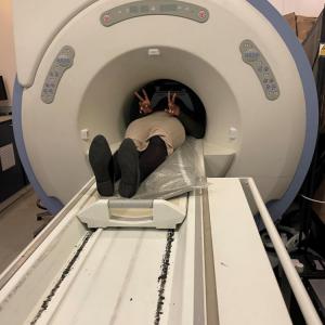 A work experience student, disappearing into a mock MRI scanner, but seeming happy about it