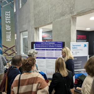 A group of people listen to one of our team discussing her poster